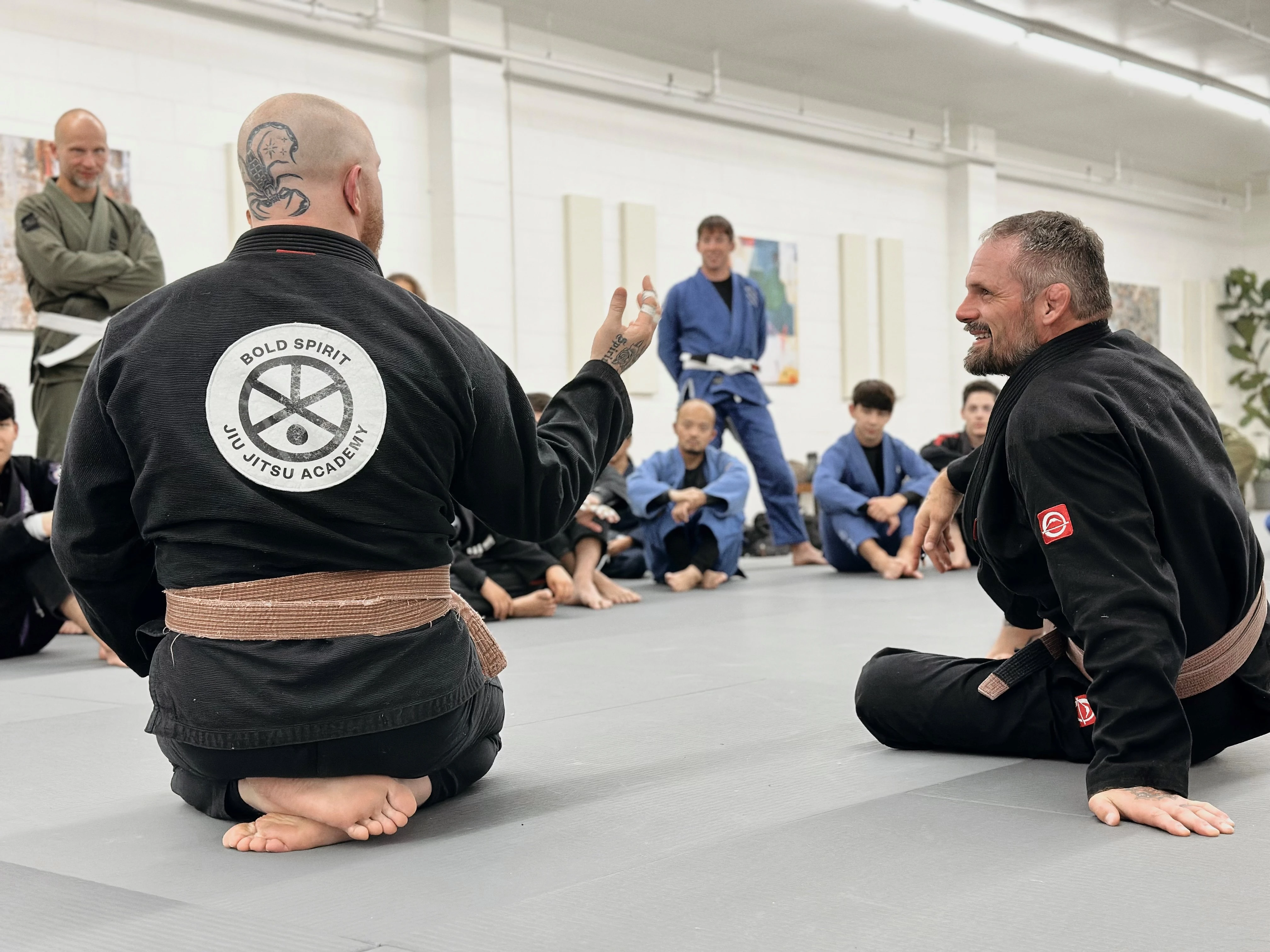 Two grapplers doing no-gi Brazilian jiu-jitsu in a gym