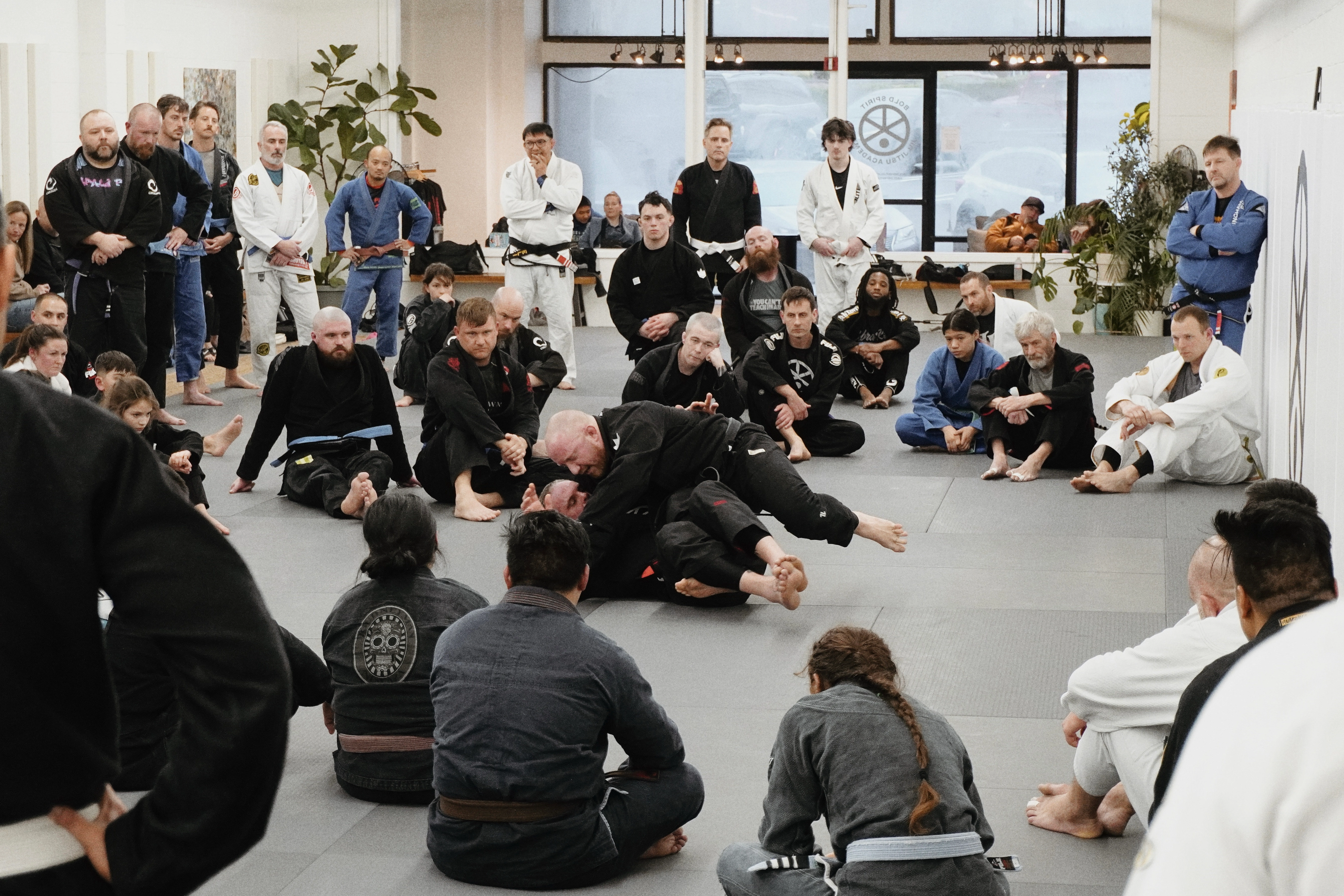 Two grapplers doing no-gi Brazilian jiu-jitsu in a gym