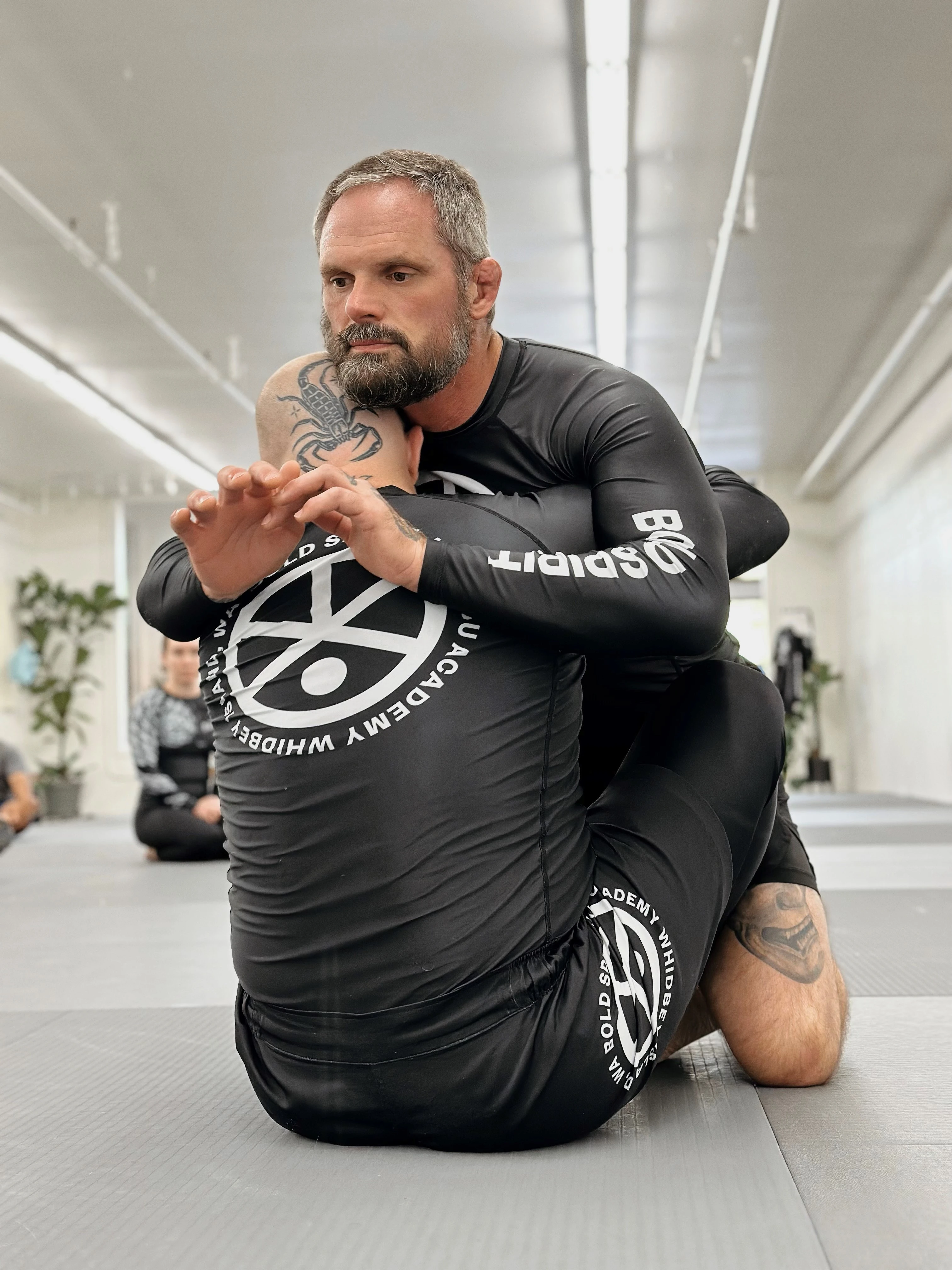 Instructor teaching a jiu-jitsu class in a gym